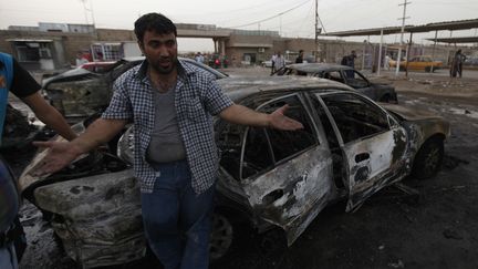 Un homme constate les d&eacute;g&acirc;ts apr&egrave;s un attentat &agrave; la voiture pi&eacute;g&eacute;e perp&eacute;tr&eacute; lundi 27 mai 2013 &agrave; Bagdad (Irak). (THAIER AL-SUDANI / REUTERS)