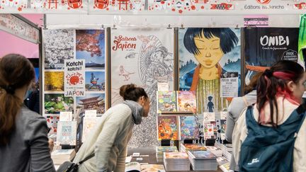 Des visiteurs regardent une bande dessinée des Editions Issekinicho dans la section Manga City lors du 49e Festival international de la bande dessinée d'Angoulême, à Angoulême, dans l'ouest de la France, le 19 mars 2022. (YOHAN BONNET / AFP)