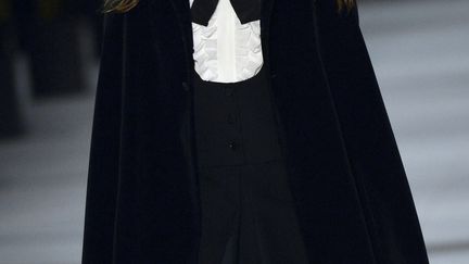 Des capes. Chez Saint Laurent et Valentino, la cape habille la silhouette et donne un air mystérieux à la femme qui la porte. Avec Hedi Slimane, chez Saint Laurent, elle est courte, noire, rouge, pailletée, écossaise ou en fourrure et se porte sur une mini-robe et avec des bottes. Avec Valentino, la cape est assortie à la jupe droite et courte. Des oiseaux sont brodés sur une cape marine, des papillons sur une longue grise. 
 (MIGUEL MEDINA / AFP)