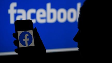 Une personne tenant un téléphone avec le logo de Facebook, à Arlington (Virginie, Etats-Unis), le 7 avril 2021. (OLIVIER DOULIERY / AFP)