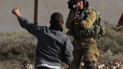 Un soldat isra&eacute;lien (D) met en joue un manifestant palestinien pr&egrave;s de Ramallah (Cisjordanie), le 31 janvier 2014. (ABBAS MOMANI / AFP)