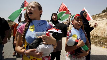 &nbsp; (Des jeunes filles tiennent des poupées dans les bras en référence au bébé palestinien brûlé vif. Elles manifestaient vendredi 7 août contre les colonies juives sur la rive ouest de Nabi Saleh, près de Ramallah © REUTERS/Mohamad Torokman)