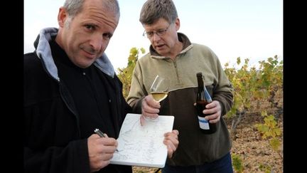 FRANCE, Rablay-sur-Layon : Etienne Davodeau (G), dessinateur de bandes dessinées, dessine près de Richard Leroy, vigneron, le 20 octobre 2011, à Rablay-sur-Layon. Pendant plus d&#039;une année, Etienne Davodeau a arpenté bottes aux pieds les vignes de Richard Leroy tout en faisant découvrir au vigneron angevin l&#039;univers de la bande dessinée : de cette initiation croisée est né un album: &quot;les Ignorants&quot;.
 (Franck Perry / AFP)