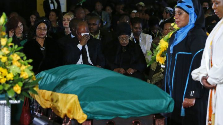 Le pr&eacute;sident sud-africain essuie ses larmes, assis aux c&ocirc;t&eacute;s des ex-&eacute;pouses de Nelson Mandela,&nbsp;Winnie Madikizela-Mandela&nbsp;et&nbsp;Gra&ccedil;a Machel, face au cercueil du prix Nobel de la pix,&nbsp;lors d'une c&eacute;r&eacute;monie &agrave; l'a&eacute;roport militaire proche de Pretoria (Afrique du Sud), le 14 d&eacute;cembre 2013. (YVES HERMAN / REUTERS)