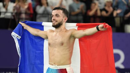 Sans tee-shirt mais avec le drapeau tricolore en mains, Charles Noakes savoure sa médaille d'or en badminton, lors des Jeux paralympiques de Paris, le 2 septembre 2024. (MAXPPP)