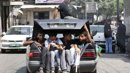 A Gaza, des Palestiniens entass&eacute;s dans une Mercedes suivent la voiture du joueur de football Mahmoud Al-Sarsak&nbsp;lib&eacute;r&eacute; par Isra&euml;l apr&egrave;s quatre mois de&nbsp;gr&egrave;ve de la faim, le 10 juillet 2012. (MOHAMMED SALEM / REUTERS)