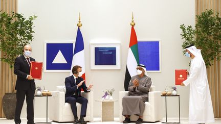 Emmanuel Macron (à gauche) et le prince héritier d'Abu Dhabi Mohammed bin Zayed al-Nahyan (à droite) se voient présenter l'accord pour l'achat de 80 avions de chasse Rafale, à Dubai le 3 décembre 2021. (THOMAS SAMSON / AFP)