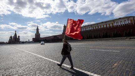 A Moscou (Russie), cet homme seul a traversé la place Rouge désertée en&nbsp;laissant flotter derrière lui&nbsp;un drapeau du Parti communiste. (YURI KADOBNOV / AFP)