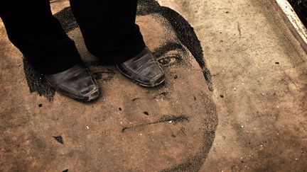 Un Tunisien marche sur le portrait de l'ancien pr&eacute;sident tunisien Ben Ali dans les rues de Tunis (Tunisie), en avril 2011. (AUDE OSNOWYCZ / SIPA)