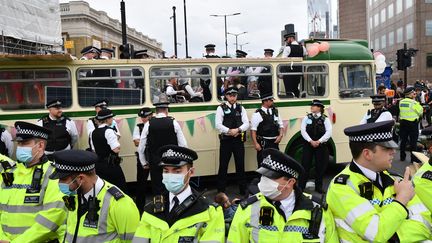 Des policiers entourent un véhicule garé en travers de la route, alors que des activistes climatiques du groupe Extinction Rebellion bloquent la route sur le London Bridge, dans le centre de Londres, le 31 août 2021. (JUSTIN TALLIS / AFP)