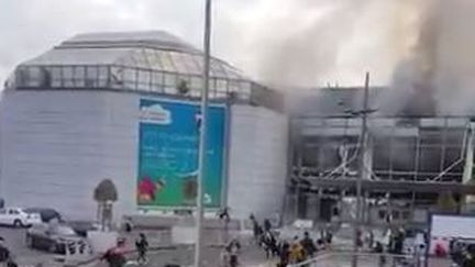 Capture d'écran d'une vidéo montrant de la fumée qui s'échappe de l'aéroport international de Bruxelles (Belgique), le 22 mars 2016. (ANNA AHRONHEIM / TWITTER)