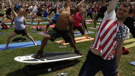 Le joueur de billard professionnel philippin&nbsp;Francisco Bustamante (C) participe &agrave; un cours de yoga collectif sur une machine &agrave; surfer, Ottawa (Canada), le 31 juillet 2013. (CHRIS WATTIE / REUTERS)