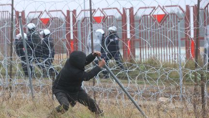 Un migrant tente de détruire les barbelés à la frontière entre la Biélorussie et la Pologne, le 16 novembre 2021. (LEONID SHCHEGLOV / BELTA)