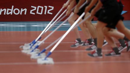 Pendant le match de volleyball Tunisie-Serbie le 1er ao&ucirc;t lors des JO de Londres, des volontaires nettoient le terrain au pas de course&nbsp; (IVAN ALVARADO / REUTERS)