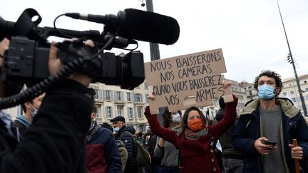 Une manifestante tient un panneau à Marseille, lors d'une manifestation contre les violences policières et la proposition de loi sur la "sécurité globale",&nbsp;le 28 novembre 2020. (NICOLAS TUCAT / AFP)