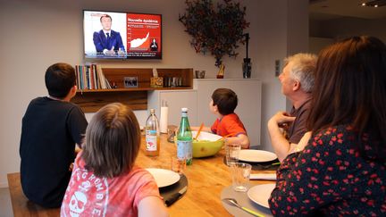 Une famille attablée regarde l'allocution du président le 31 mars 2021 annonçant des mesures pour lutter contre l'épidémie de Covid. (illustration) (VANESSA MEYER / MAXPPP)