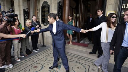 L'ancien pr&eacute;sident fran&ccedil;ais Nicolas Sarkozy (C), tiraill&eacute; entre son &eacute;pouse Carla Bruni (D) et des supporters &agrave; sa sortie de l'h&ocirc;tel Regina &agrave; Paris, le 28 juin 2012. (KENZO TRIBOUILLARD / AFP)