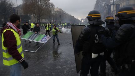 Des manifestants vêtus de gilets jaunes font face aux forces de l'ordre samedi 24 novembre&nbsp;sur les Champs-Élysées, à Paris. (CHRISTOPHE PETIT TESSON / EPA)