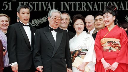 Le réalisateur japonais Shōhei Imamura, deux fois palme d'or, pose aux côtés de sa femme&nbsp;et de ses acteurs lors du festival de Cannes en 1998. (PATRICK HERTZOG / AFP)