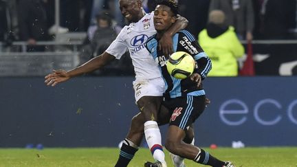 Le défenseur lyonnais Mapou Yanga-Mbiwa à la lutte avec l'attaquant de l'OM Michy Batshuayi (PHILIPPE DESMAZES / AFP)