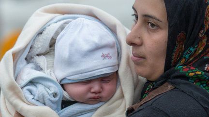 Une mère et son bébé ayant fui l'Afghanistan attendent du côté autrichien de la frontière germano-autrichienne de près de Wegscheid, le 30 octobre 2015. (Photo DPA /AFP signée Armin Weigel)