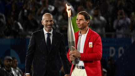 L'un était attendu, l'autre un peu moins... Zinédine Zidane a transmis la flamme olympique à l'Espagnol Rafael Nadal, 14 fois vainqueur de Roland-Garros. (JEFF PACHOUD / AFP)