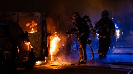 Un pompiers tente d'éteindre un véhicule en feu, incendié pendant les manifestations urbaines qui ont suivi la mort du jeune Nahel, 17 ans, tué par un policier à Nanterre (NICOLAS LIPONNE / HANS LUCAS)