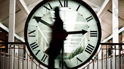 Une personne passe devant une horloge, le 25 mars 2010 au centre commercial de la Toison d'Or, à Dijon. (JEFF PACHOUD / AFP)