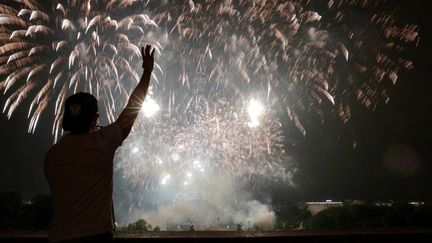 Un homme assiste au&nbsp;feu d'artifice au-dessus de la Tour Eiffel dans le cadre des célébrations annuelles&nbsp;du 14-Juillet à Paris, le 14 juillet 2021. (GEOFFROY VAN DER HASSELT / AFP)