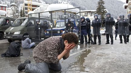 Une femme se rince les yeux avec de l'eau d'une mare apr&egrave;s avoir &eacute;t&eacute; asperg&eacute;e de gaz lacrymog&egrave;ne lors d'une manifestation en marge du forum &eacute;conomique de Davos (Suisse), le 28 janvier 2012. (MIRO KUZMANOVIC / REUTERS)