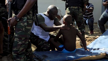 Un soldat ivoirien réconforte un enfant après l'attaque contre trois hôtels dans la station balnéaire de Grand-Bassam (Côte d'Ivoire), le 13 mars 2016. (JOE PENNEY / REUTERS)