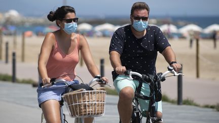 Un couple de cyclistes le long de la plage à Barcelone&nbsp;(Espagne), le 18 juillet 2020. (JOSEP LAGO / AFP)