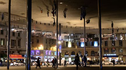 Des pi&eacute;tons se refl&egrave;tent dans l'oeuvre de l'architecte britannique Norman Foster sur le Vieux-Port &agrave; Marseille (Bouches-du-Rh&ocirc;ne), le 5 novembre 2013. (ANNE-CHRISTINE POUJOULAT / AFP)