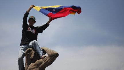 Un partisan d'Hugo Chavez juch&eacute; sur une statue devant l'Acad&eacute;mie militaire o&ugrave; se d&eacute;roulent les obs&egrave;ques du pr&eacute;sident &agrave; Caracas le 8 mars 2013. ( MAXPPP)