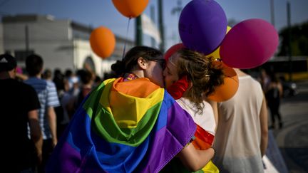 Un couple drapé dans un drapeau arc-en-ciel s'embrasse durant la Gay Pride de Lisbonne (Portugal), le 17 juin 2017. (PATRICIA DE MELO MOREIRA / AFP)