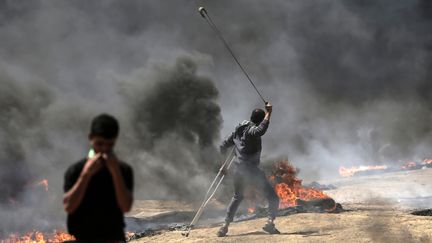 Un Palestinien utilise une fronde pendant les affrontements avec les forces israéliennes, à Gaza. (MAHMUD HAMS / AFP)