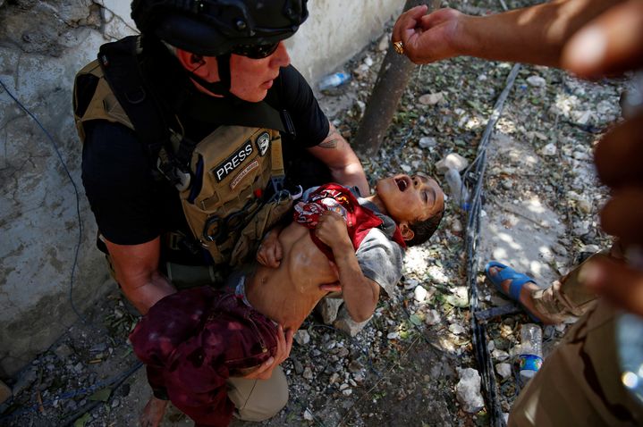 Des militaires versent de l'eau sur la tête d'un enfant déshydraté et amaigri après l'avoir secouru, dans la vieille ville de Mossoul (Irak), le 13 juin 2017.&nbsp; (ERIK DE CASTRO / REUTERS)