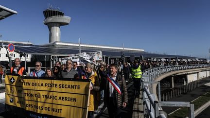 Des manifestants derrière une pancarte protestent contre la fermeture d'une piste de l'aéroport de Bordeaux-Mérignac (Gironde), le 28 septembre 2024, craignant une hausse de la pollution sonore au dessus de leur tête. (THIBAUD MORITZ / AFP)