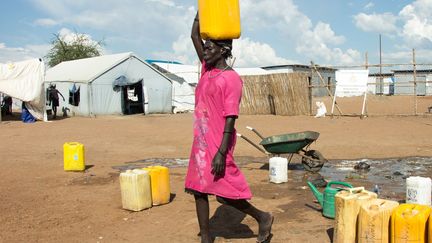 une déplacée sud-soudanaise transporte de l'eau, le 17 novembre 2018. Ce camp situé à la périphérie de Juba abrite des milliers de civils en errance dont la plupart appartiennent à l'ethnie nuer. Les premiers d'entre eux sont arrivés à la mi-décembre 2013, lorsque le pays a sombré dans la guerre civile: le président Salva Kiir, un Dinka, accusait alors Riek Machar, son ancien vice-président, de l'ethnie nuer, de préparer un coup d'Etat. Après un accord de paix qui a échoué en 2015, les deux belligérants en ont signé un nouveau, en septembre 2018. Si cette réconciliation laisse sceptique les observateurs, le gouvernement sud-soudanais a affirmé, le 21 novembre, que la production pétrolière avait déjà augmenté de 20.000 barils par jour en à peine deux mois. Le Soudan du Sud dépend des raffineries soudanaises pour l'exportation de son pétrole. (AKUOT CHOL / AFP)