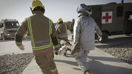 A sa descente d'hélicoptère, le blessé est immédiatement transporté par des pompiers secouristes vers une ambulance. (AFP PHOTO / BEHROUZ MEHRI)