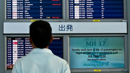 Un Malaisien face &agrave; un &eacute;cran qui rend hommage aux passagers du vol MH17, qui s'est &eacute;cras&eacute; le 17 juillet 2014 dans l'Est de l'Ukraine, &agrave; l'a&eacute;roport de Kuala Lumpur.&nbsp; (MANAN VATSYAYANA / AFP)