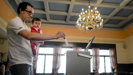 A Bulle, dans l'ouest de la Suisse, un &eacute;lecteur vote le dimanche 18 mai 2014 durant le r&eacute;f&eacute;rendum qui doit d&eacute;cider l'introduction dans le pays d'un salaire minimum de 3 300 euros.&nbsp; (FABRICE COFFRINI / AFP)