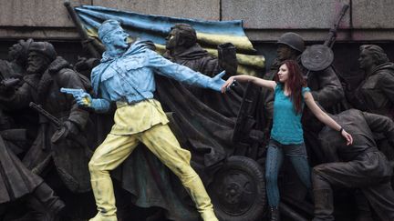 Une femme pose devant un monument repr&eacute;sentant des soldats sovi&eacute;tiques et repeint aux couleurs de l'Ukraine &agrave; Sofia (Bulgarie), le 23 f&eacute;vrier 2014. (REUTERS)