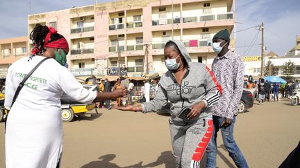 Des bénévoles distribuent du gel hydroalcoolique à des passants, à Dakar (Sénégal), le 22 janvier 2021. (SEYLLOU / AFP)