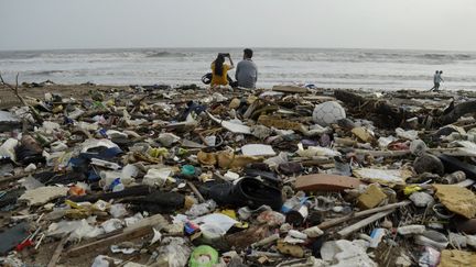 Un couple au milieu des détritus profite d'un peu de répit entre deux averses sur une plage de Bombay (Mumbai), le 8 juillet 2023. (INDRANIL ADITYA / NURPHOTO / AFP)