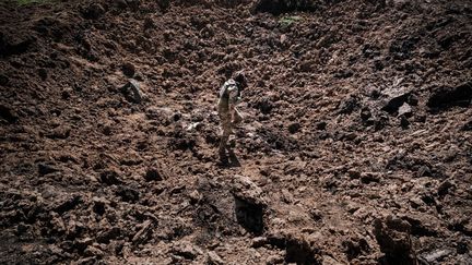 Un militaire inspecte un cratère après une frappe de missile russe à Bohodarove, dans l'est de l'Ukraine, le 25 avril 2022. (YASUYOSHI CHIBA / AFP)