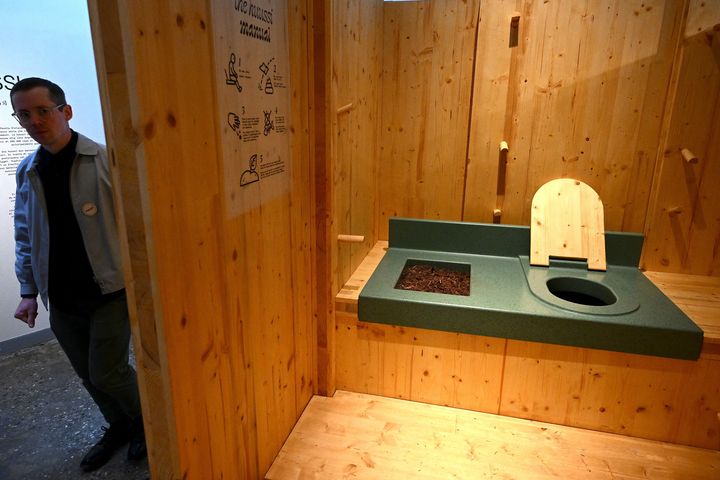 Un visiteur consulte l'installation "Huussi" une toilette sèche finlandaise, lors de la 18e Biennale internationale d'architecture de Venise le 17 mai 2023 (VINCENZO PINTO / AFP)