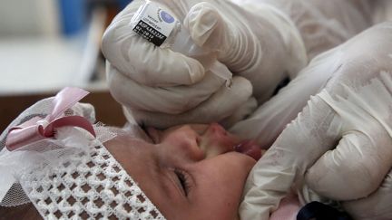 An UNRWA worker administers a dose of polio vaccine to a child in Gaza, September 2020. Illustrative. (MOHAMMED ABED / AFP)