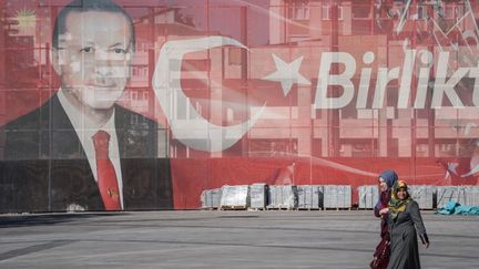 Deux femmes marchent devant une grande affiche dans la rue montrant le président turc Recep Tayyip Erdogan à Konya, en Turquie, le 27 octobre 2018 (illustration). (DIEGO CUPOLO / NURPHOTO / AFP)