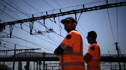 Des employés de la SNCF se tiennent sous des lignes électriques à la gare de Bordeaux, le 15 juin 2022. (PHILIPPE LOPEZ / AFP)